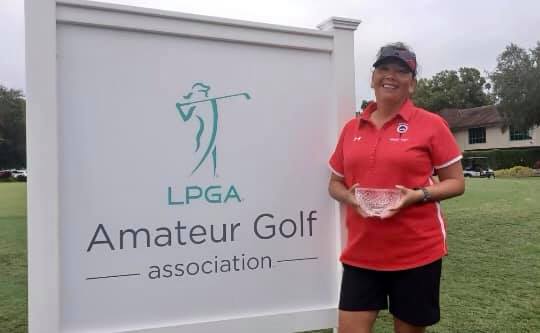 Linda Costello with her prize bowl standing by the LPGA Amateurs logo sign