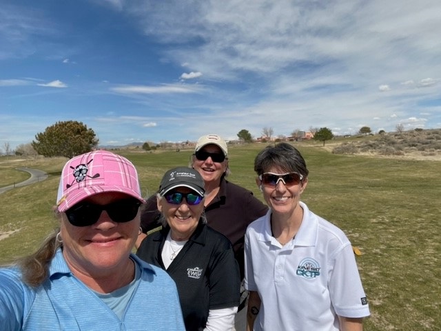 Four women smiling on a sunny day at Arroyo del Oso golf course in Albuquerque, New Mexico