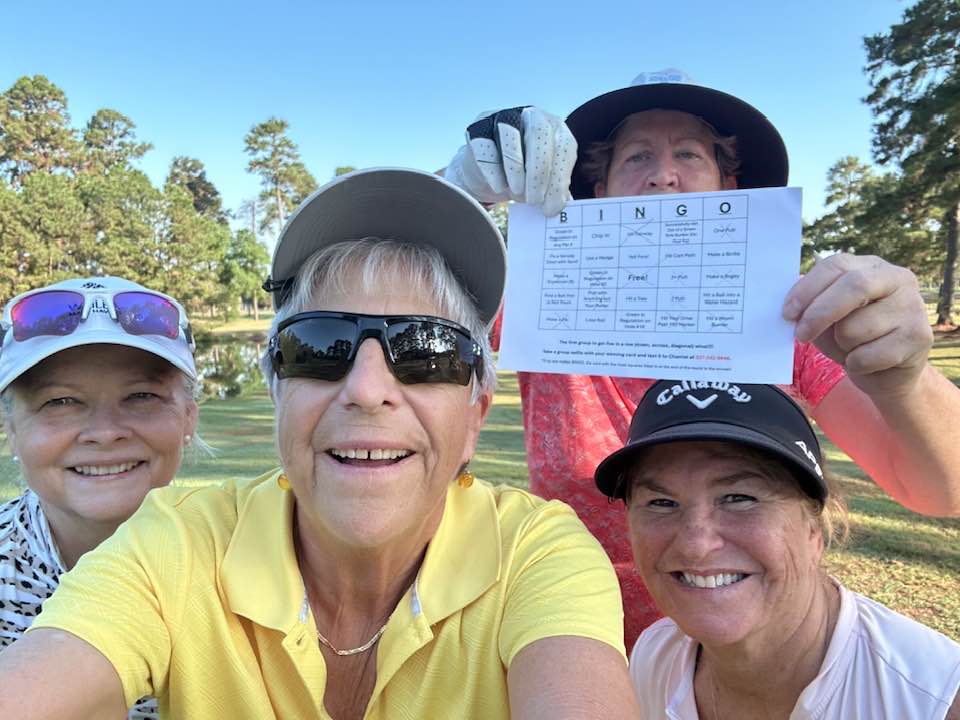 A group of female golfers taking a selfie during a round of golf in Houston Texas. Golf bingo card on display.