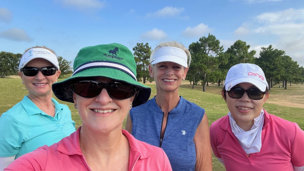 Four female golfers posing on the tee box during a round of golf in Houston Texas