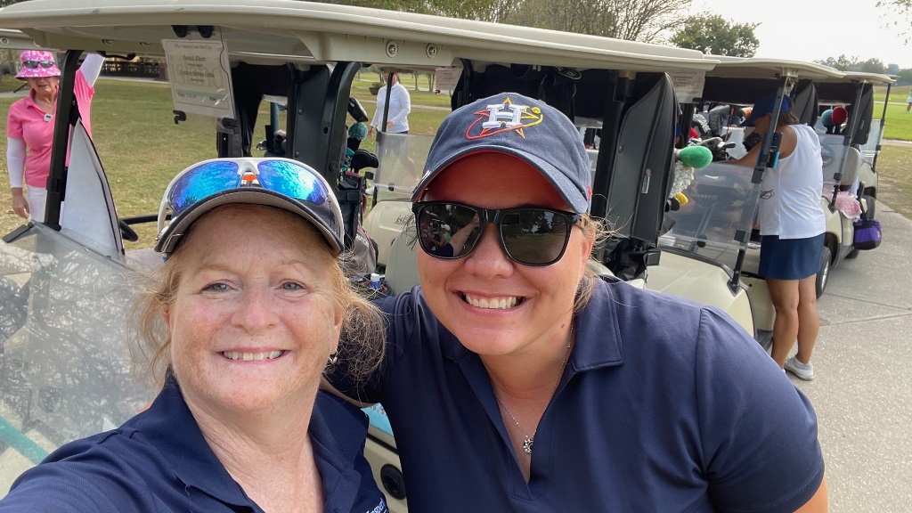 Two female golfers in Houston Astros hats posing taking a selfie before a golf tournament in Houston Texas