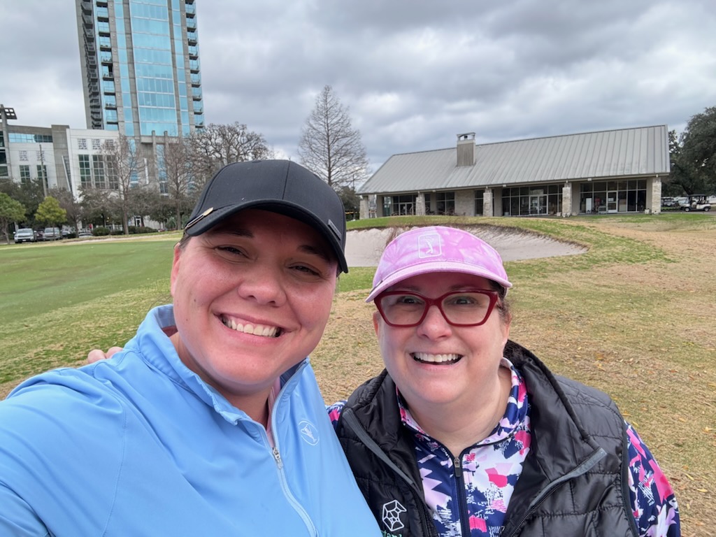 Two female golfers taking a selfie during a round of golf in Houston Texas with the city skyline in the background