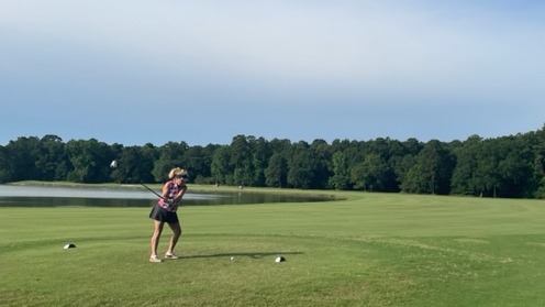 A female golfer teeing off at a beautiful lakeside golf course in Houston Texas