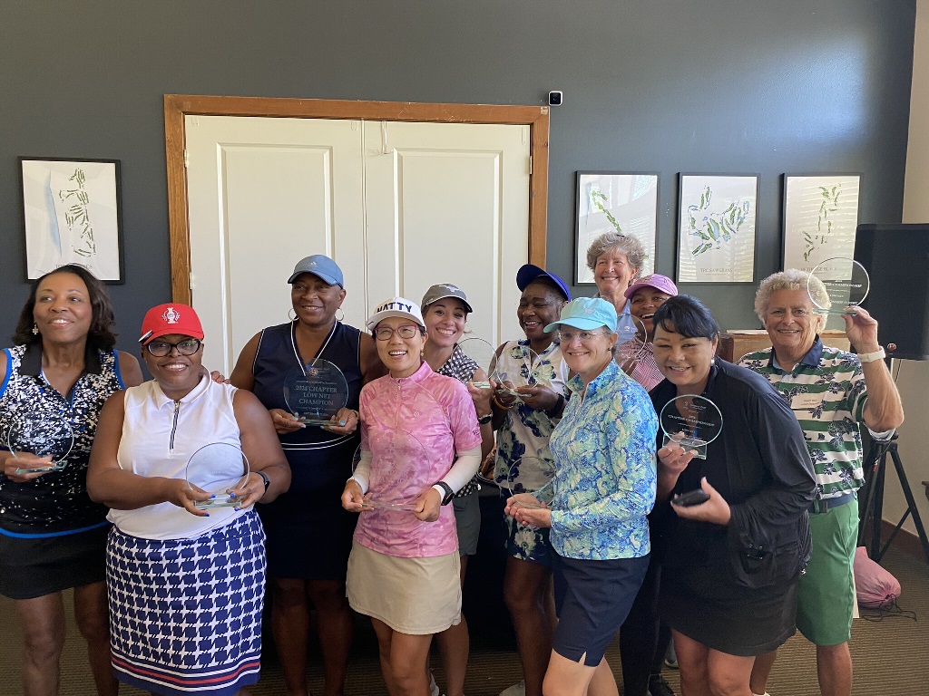 A group of female golfers posing for a picture with their awards after competing in a golf tournament in Houston Texas