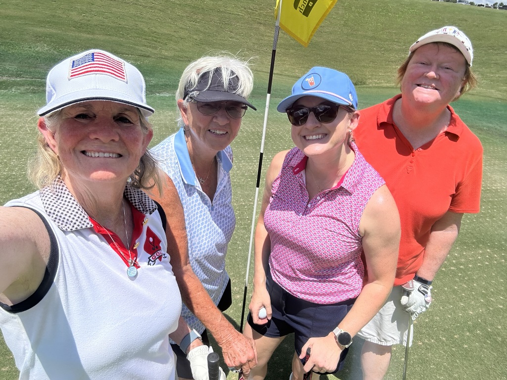 Four female golfers taking a selfie on the green during a round of golf in Houston Texas