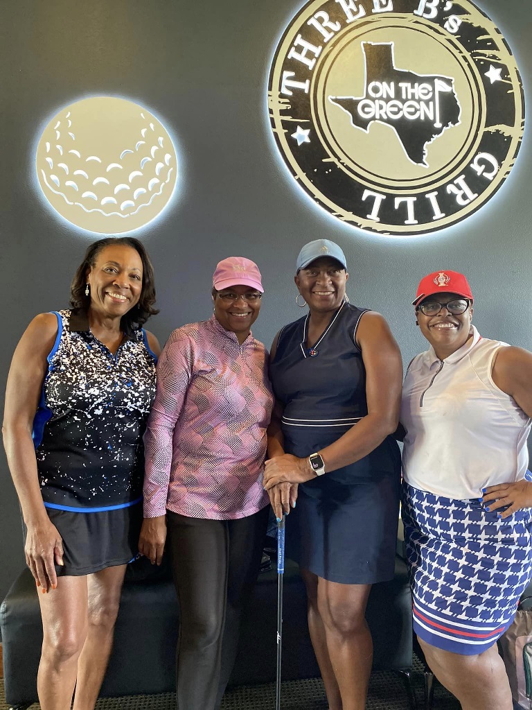 Four female golfers posing for a picture during an event at a grill & golf simulator in Houston Texas
