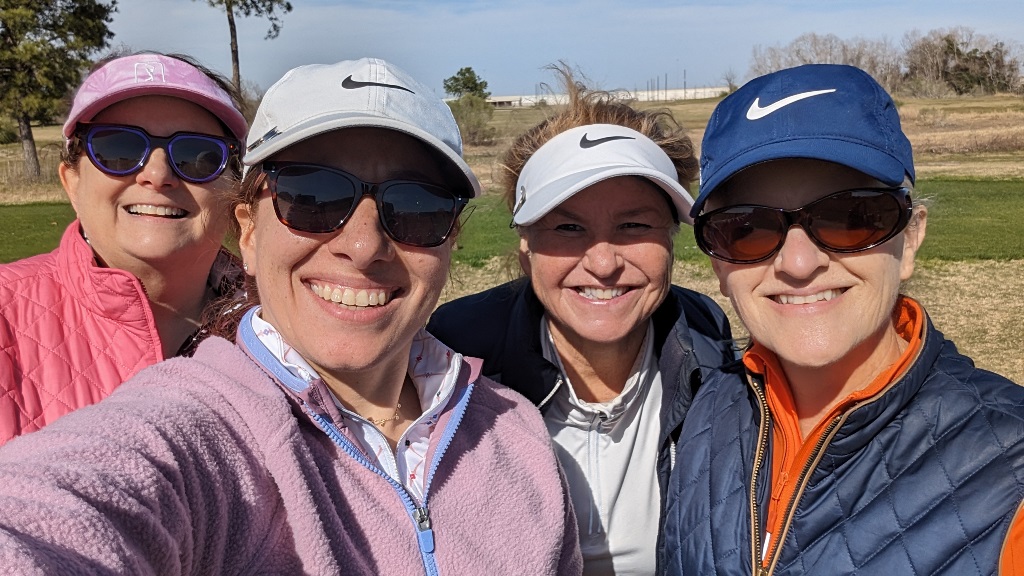 Four female golfers taking a group selfie while playing golf on a chilly day in Houston Texas