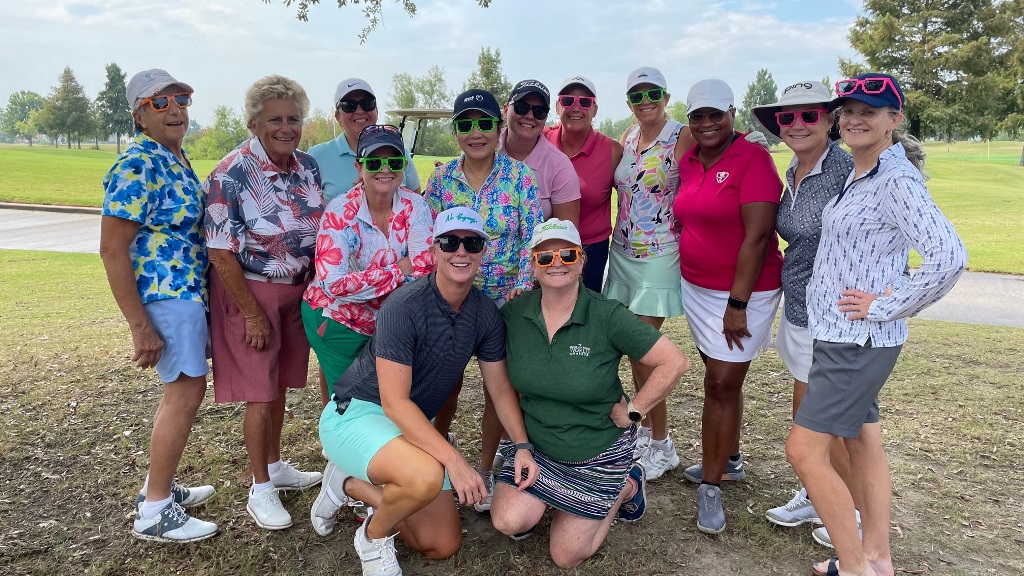 A group of female golfers wearing matching sunglasses posing for a team photo before a golf tournament in Houston Texas