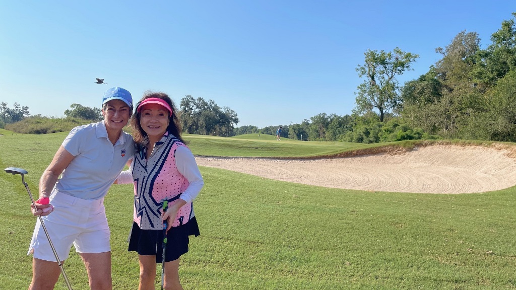 Two female golfers during a round of golf near a sand trap bunker in sunny Houston Texas