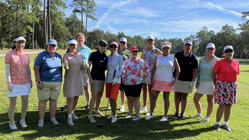 A group of female golfers posing for a team photo during an event on a sunny day in Houston Texas